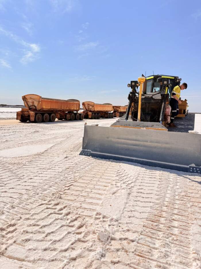 Motor grader working a haul road with road train trailers behind